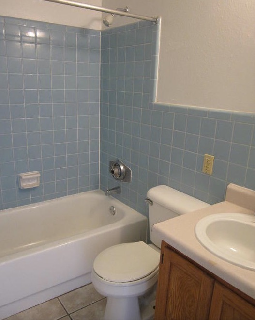 Tiles line the wall of the shower and the wall behind the toilet and vanity in the bathroom of the two-bedroom rental. 
