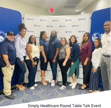 Simply Healthcare Round Table Talk Event. Group of men and women standing in front of signage.