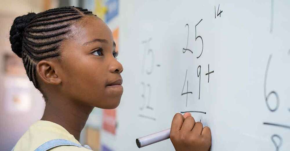 A girl doing math on a whiteboard.