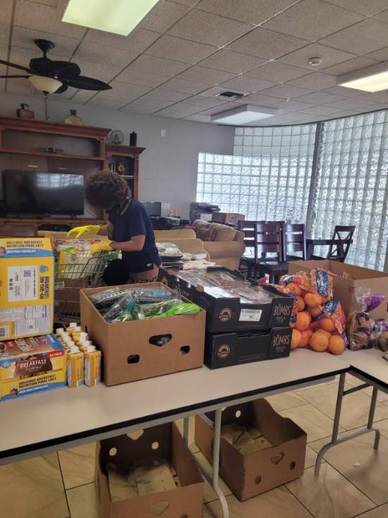 Assorted fruits and vegetables sitting in boxes on tables.