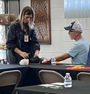 Two people behind a table, one taking the others blood pressure.