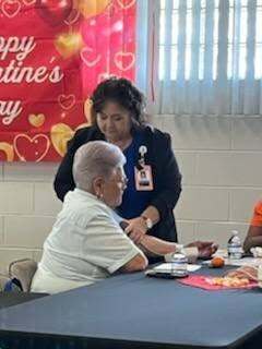 Two ladies at a table, one taking the others blood pressure.