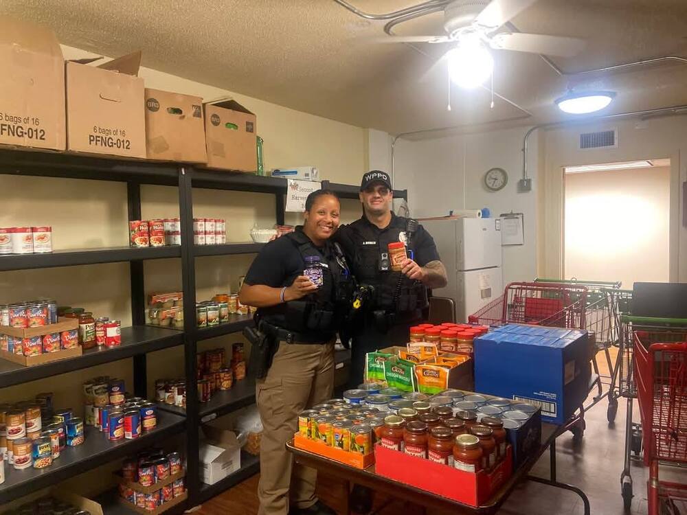 Two officer holding peanut butter and jelly in a food pantry room.