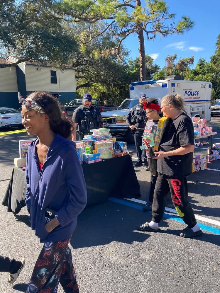 People outside walking by some tables covered with items provided by the Police Department.